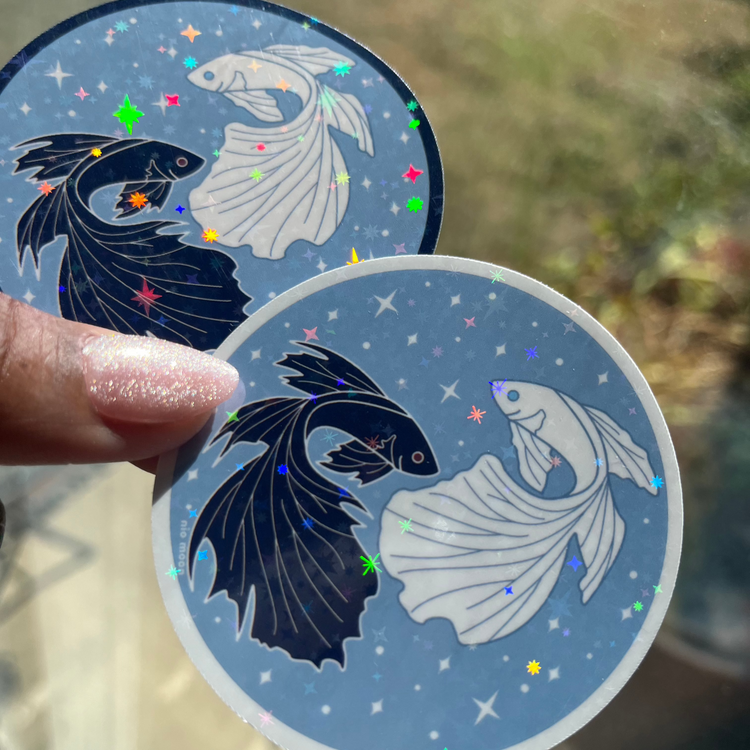 gleaming holographic stickers of black and white betta fish, one with a black outline, and one with a white outline