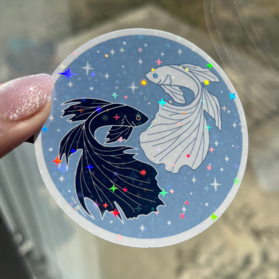 a close up photo of the white outlined sticker of gleaming holographic stickers of black and white betta fish