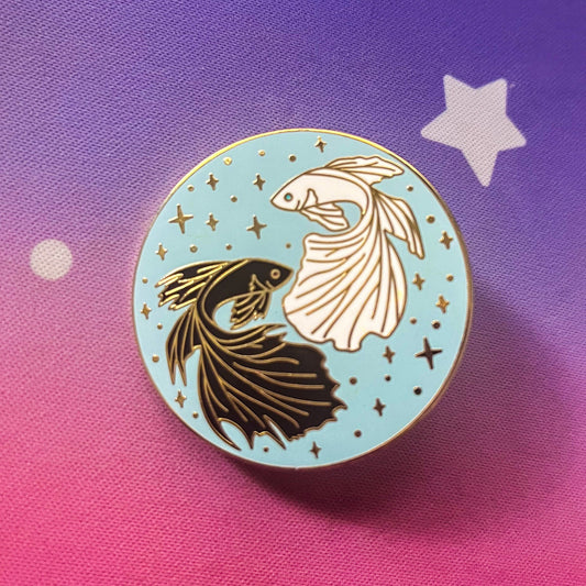 enamel pin featuring one black and one white betta fish facing each other